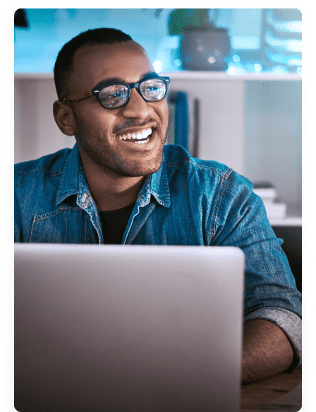 a young man smiling while working on a laptop
